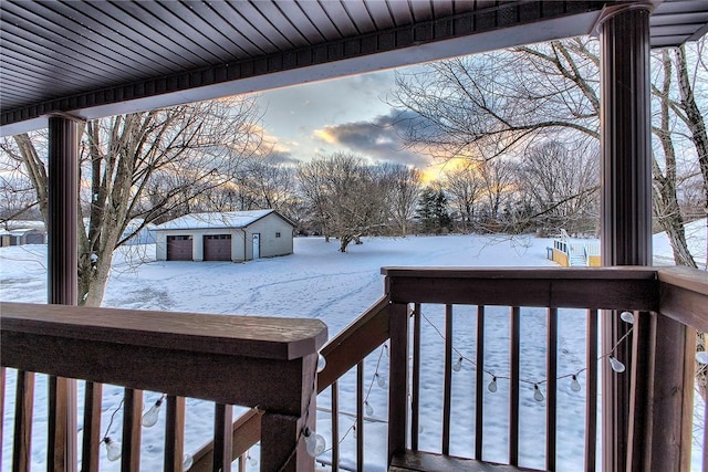 snow covered deck with a garage and an outdoor structure