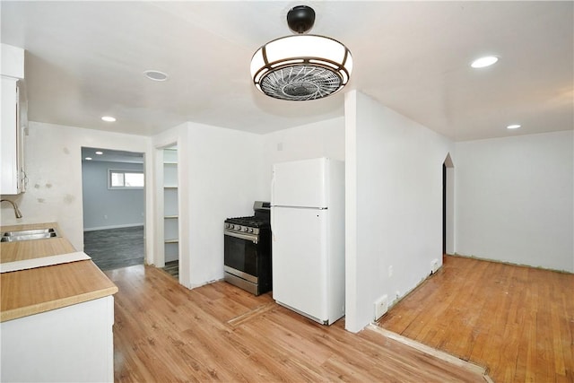 kitchen with white fridge, gas range, light hardwood / wood-style flooring, and sink