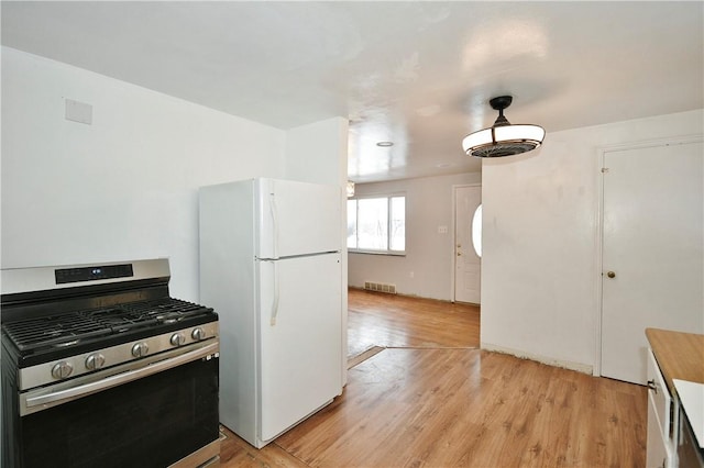 kitchen featuring white refrigerator, light wood-type flooring, and stainless steel range with gas cooktop