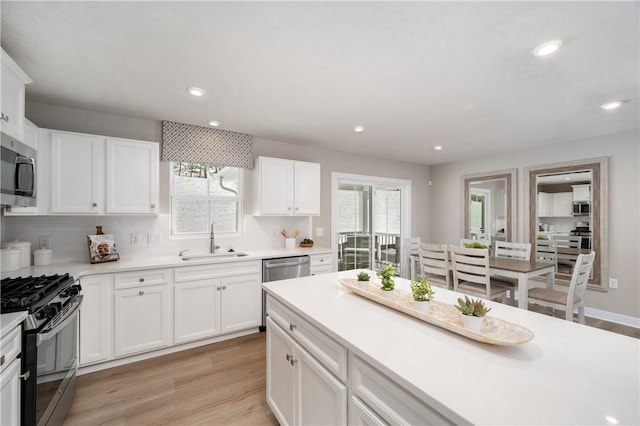 kitchen with sink, white cabinetry, light hardwood / wood-style flooring, and appliances with stainless steel finishes