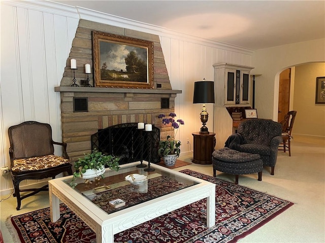 sitting room with a stone fireplace and carpet floors