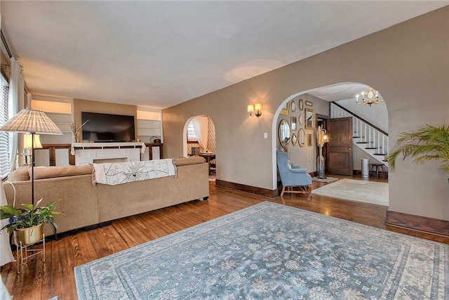 living room featuring wood-type flooring, an inviting chandelier, and built in shelves