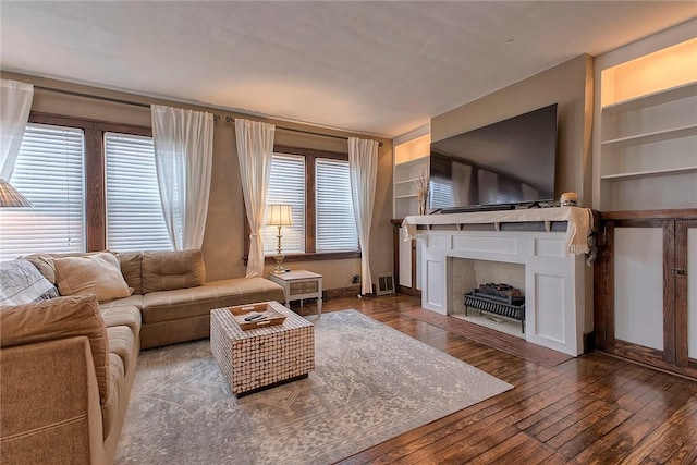 living room with dark hardwood / wood-style flooring and built in shelves