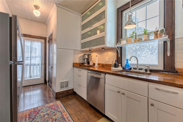 kitchen with wooden counters, stainless steel appliances, white cabinetry, and sink