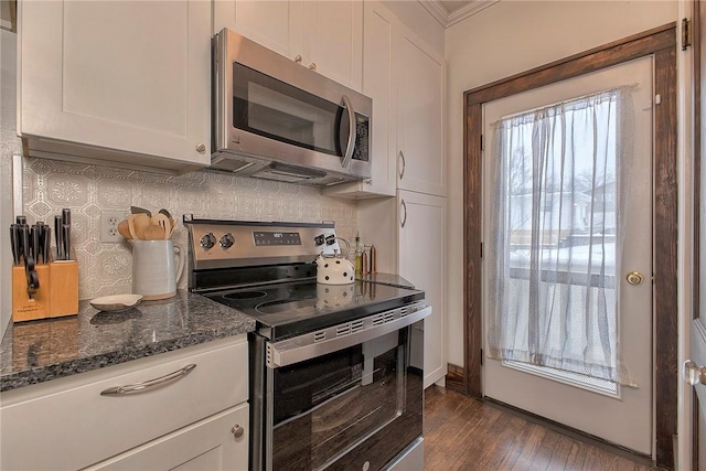 kitchen featuring stainless steel appliances, dark stone counters, dark wood-type flooring, decorative backsplash, and white cabinetry