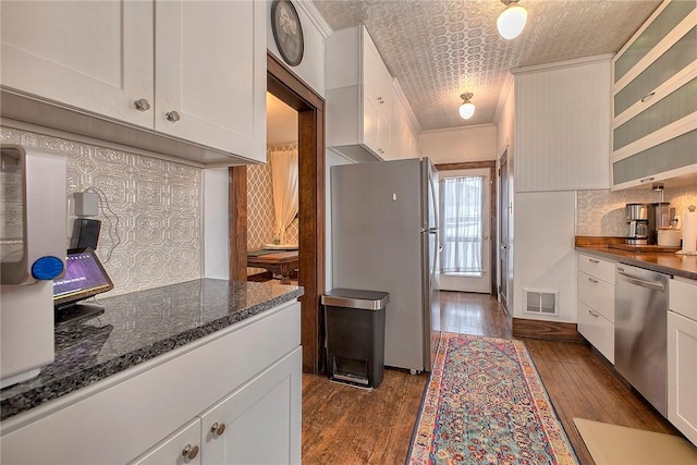 kitchen with stainless steel appliances, ornamental molding, dark hardwood / wood-style flooring, and white cabinetry