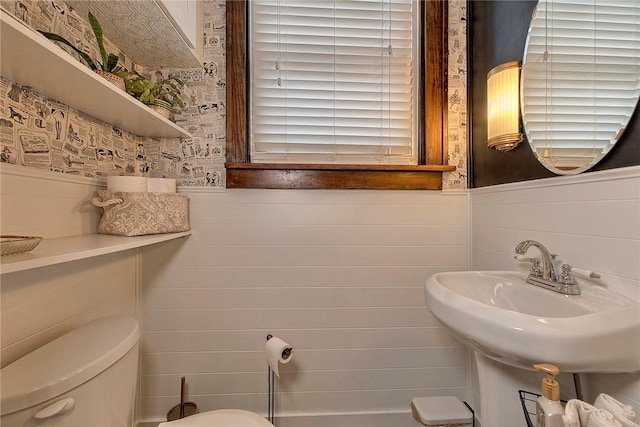 bathroom featuring sink, wooden walls, and toilet