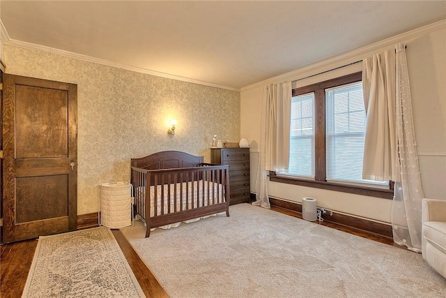 bedroom featuring crown molding, hardwood / wood-style floors, and a crib