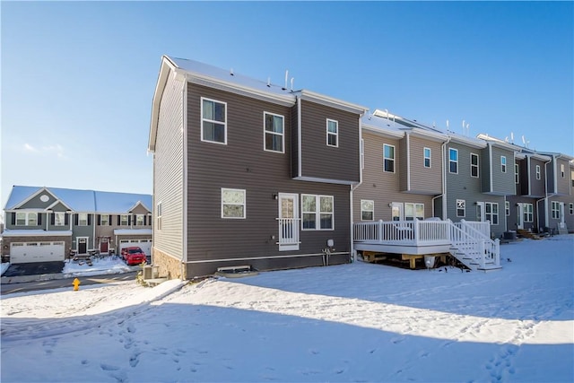 snow covered rear of property with a wooden deck