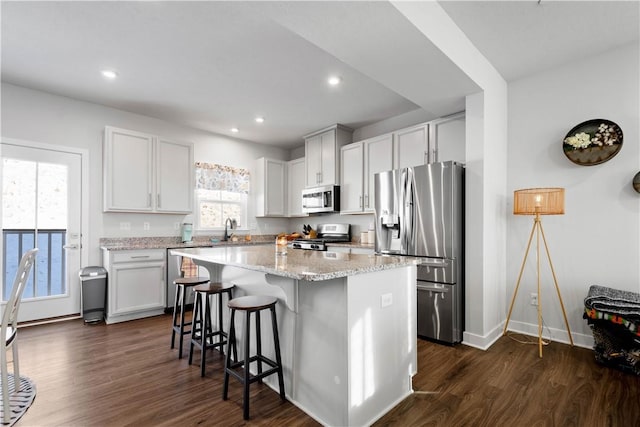 kitchen with a center island, stainless steel appliances, dark hardwood / wood-style flooring, white cabinetry, and sink