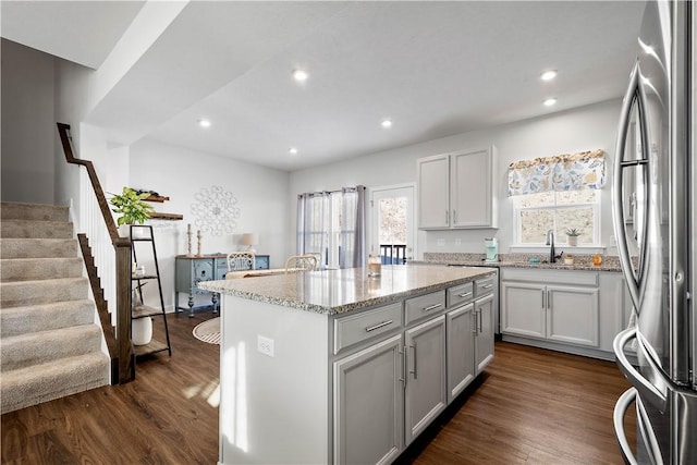 kitchen featuring light stone countertops, stainless steel fridge, dark hardwood / wood-style floors, and a kitchen island