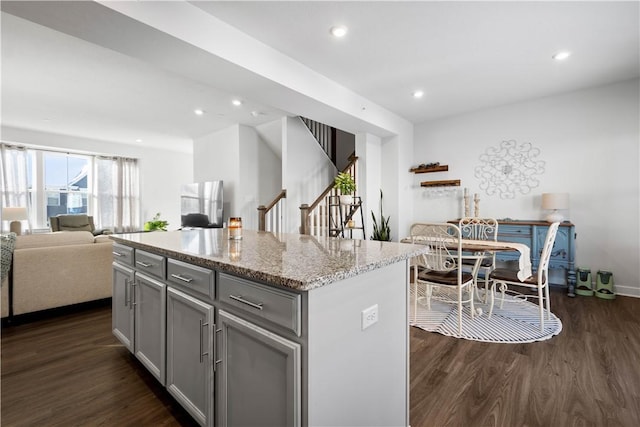 kitchen featuring gray cabinetry, dark hardwood / wood-style flooring, light stone counters, and a kitchen island