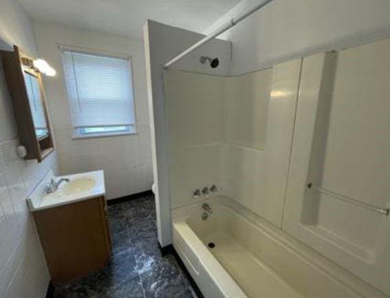 bathroom featuring tile walls, shower / bathtub combination, and vanity