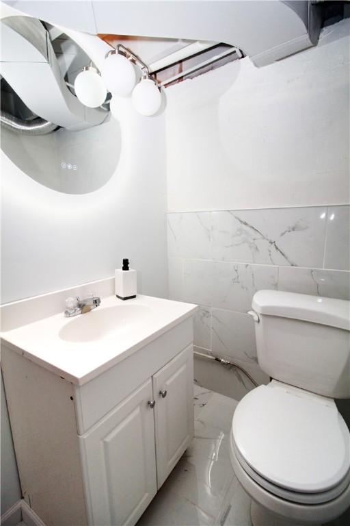 bathroom featuring tile walls, vanity, and toilet