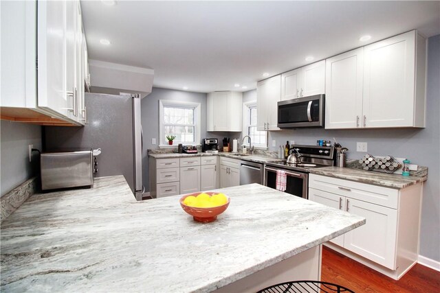 kitchen with white cabinets, kitchen peninsula, and appliances with stainless steel finishes