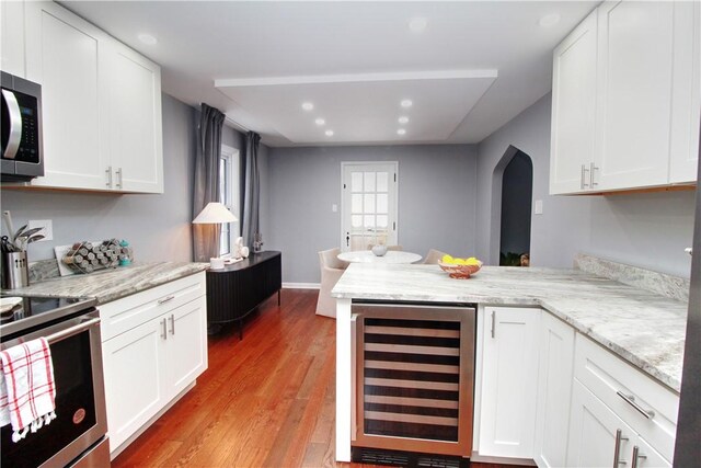 kitchen featuring white cabinets, beverage cooler, and kitchen peninsula