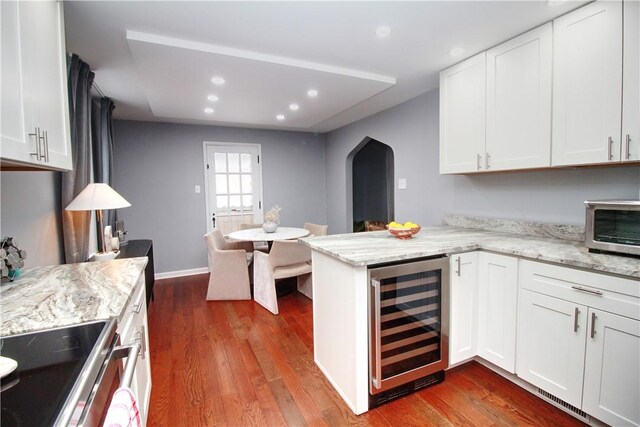 kitchen with kitchen peninsula, dark wood-type flooring, wine cooler, and white cabinets