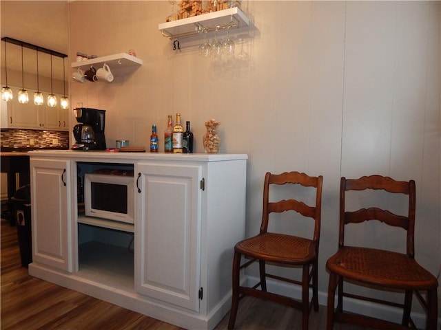 bar featuring decorative light fixtures, dark wood-type flooring, tasteful backsplash, and white cabinetry