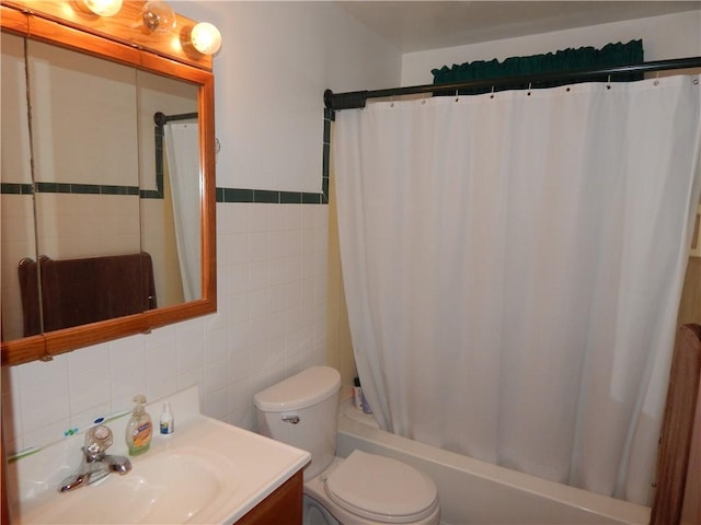 full bathroom featuring toilet, tile walls, vanity, and shower / tub combo with curtain