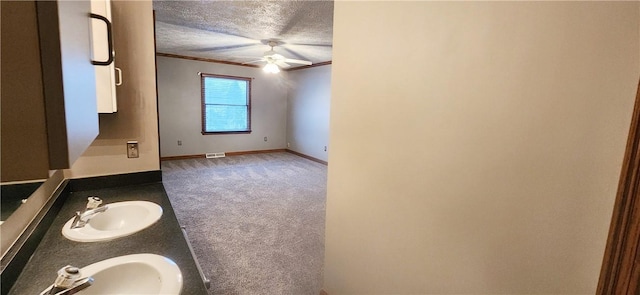 unfurnished room featuring ceiling fan, sink, dark carpet, and a textured ceiling