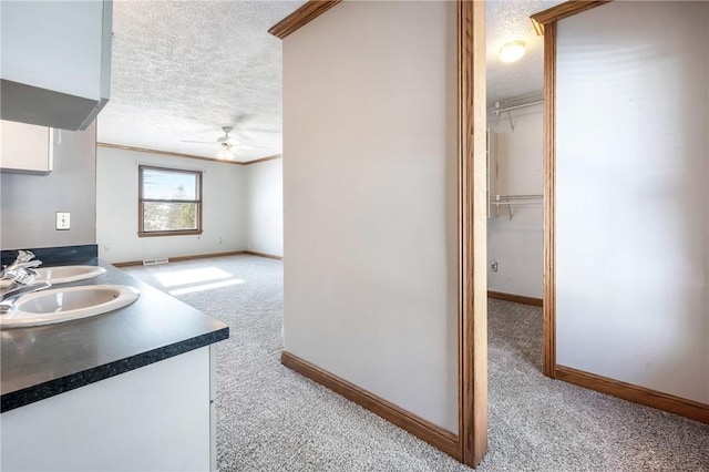 bathroom featuring ceiling fan, vanity, a textured ceiling, and ornamental molding