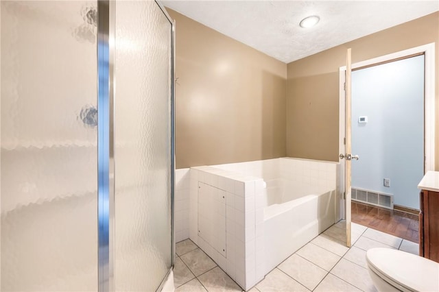 bathroom featuring a textured ceiling, tile patterned floors, toilet, and plus walk in shower