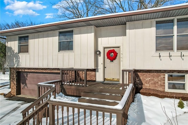 snow covered property entrance with a garage