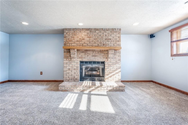 unfurnished living room featuring carpet, a brick fireplace, and a textured ceiling