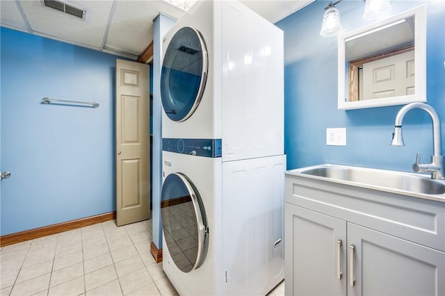 laundry room with light tile patterned floors, sink, and stacked washer and clothes dryer