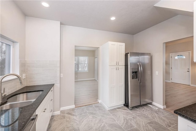 kitchen featuring sink, white cabinetry, stainless steel appliances, and dark stone counters