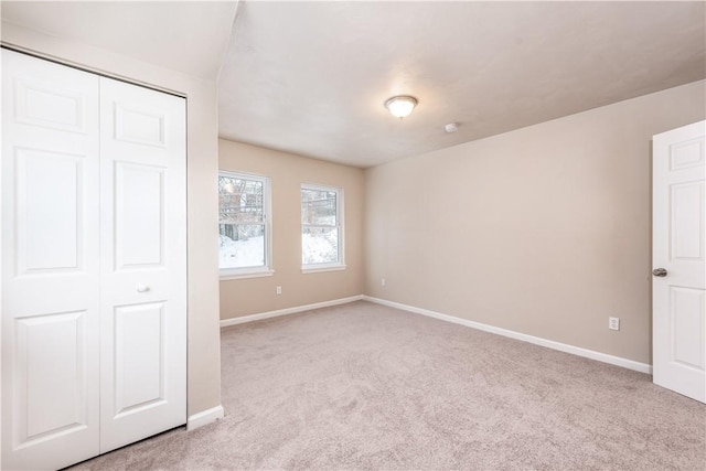 unfurnished bedroom featuring a closet and light colored carpet