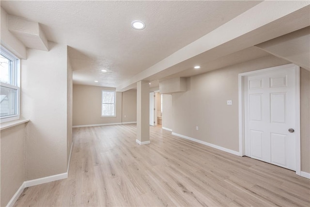 basement featuring a textured ceiling and light wood-type flooring