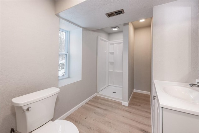 bathroom with toilet, hardwood / wood-style floors, walk in shower, a textured ceiling, and vanity