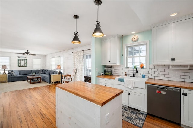 kitchen featuring dishwasher, wooden counters, pendant lighting, sink, and white cabinetry