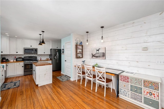 kitchen with appliances with stainless steel finishes, pendant lighting, white cabinetry, and wooden counters