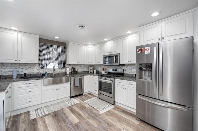 kitchen with sink, white cabinetry, light hardwood / wood-style flooring, and stainless steel appliances