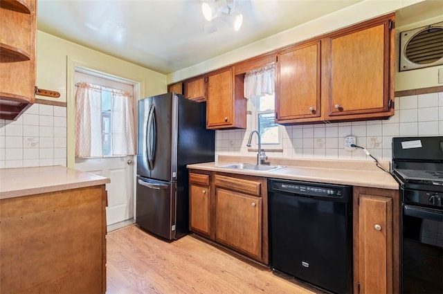 kitchen featuring black appliances, light wood-type flooring, backsplash, and sink