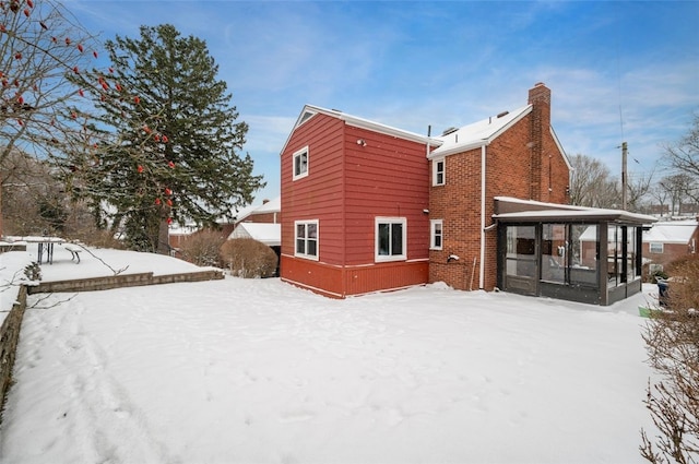 snow covered property featuring a sunroom