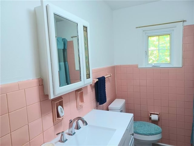 bathroom with toilet, tile walls, and sink