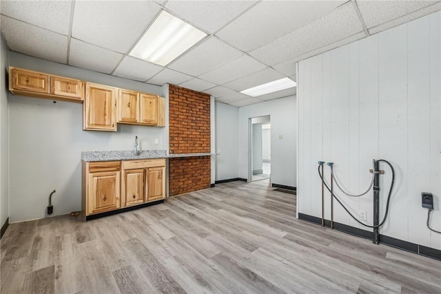 kitchen with light wood-type flooring, a drop ceiling, and sink