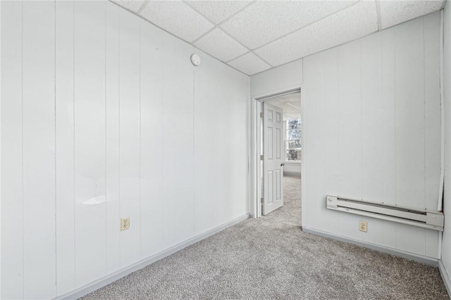 carpeted spare room with baseboard heating and a drop ceiling