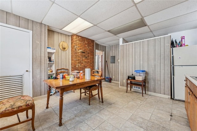 dining room with a drop ceiling and wooden walls