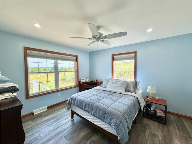 bedroom featuring ceiling fan, multiple windows, and dark hardwood / wood-style floors