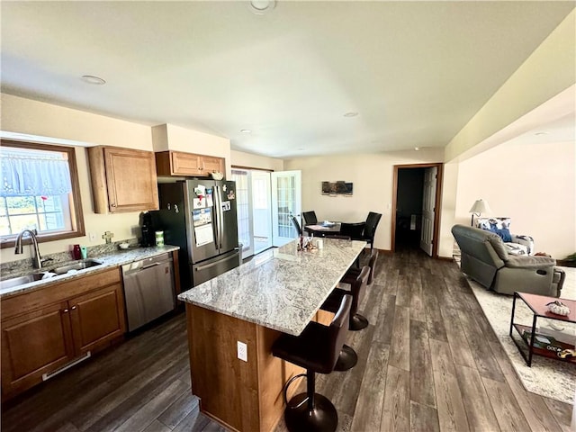 kitchen featuring dark hardwood / wood-style floors, a kitchen island, a kitchen bar, sink, and appliances with stainless steel finishes