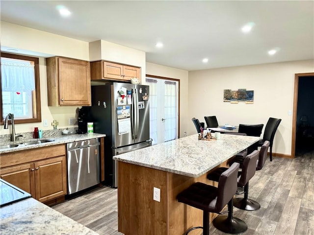 kitchen with a kitchen island, a kitchen bar, dark wood-type flooring, stainless steel appliances, and sink