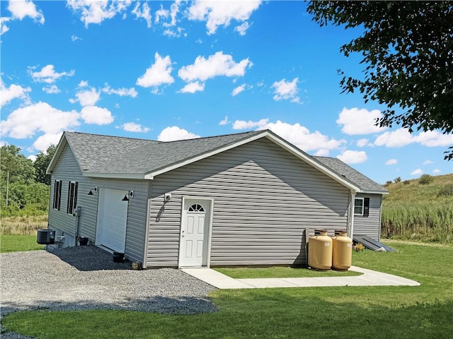 rear view of house with a garage, a yard, and central AC unit