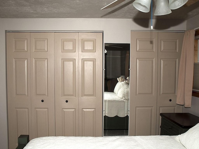 bedroom featuring a textured ceiling, ceiling fan, and multiple closets