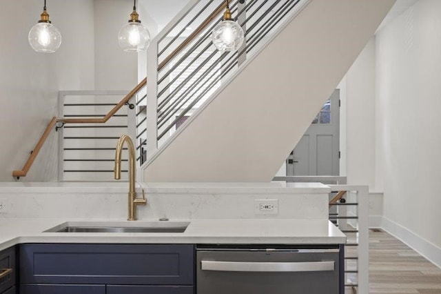 interior space with light hardwood / wood-style floors, sink, hanging light fixtures, and stainless steel dishwasher