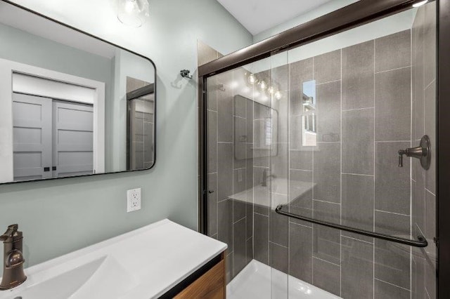 bathroom featuring a shower with shower door and vanity