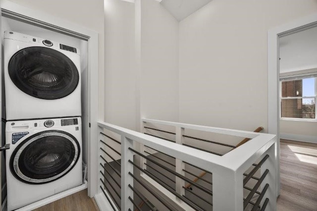 laundry area featuring stacked washer / dryer and hardwood / wood-style flooring